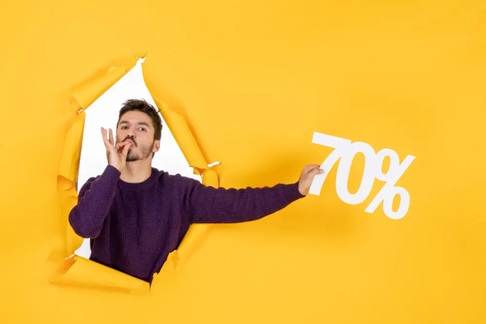 Excited shopper holding a 70% discount sign breaking through yellow paper background, representing big savings on sale items