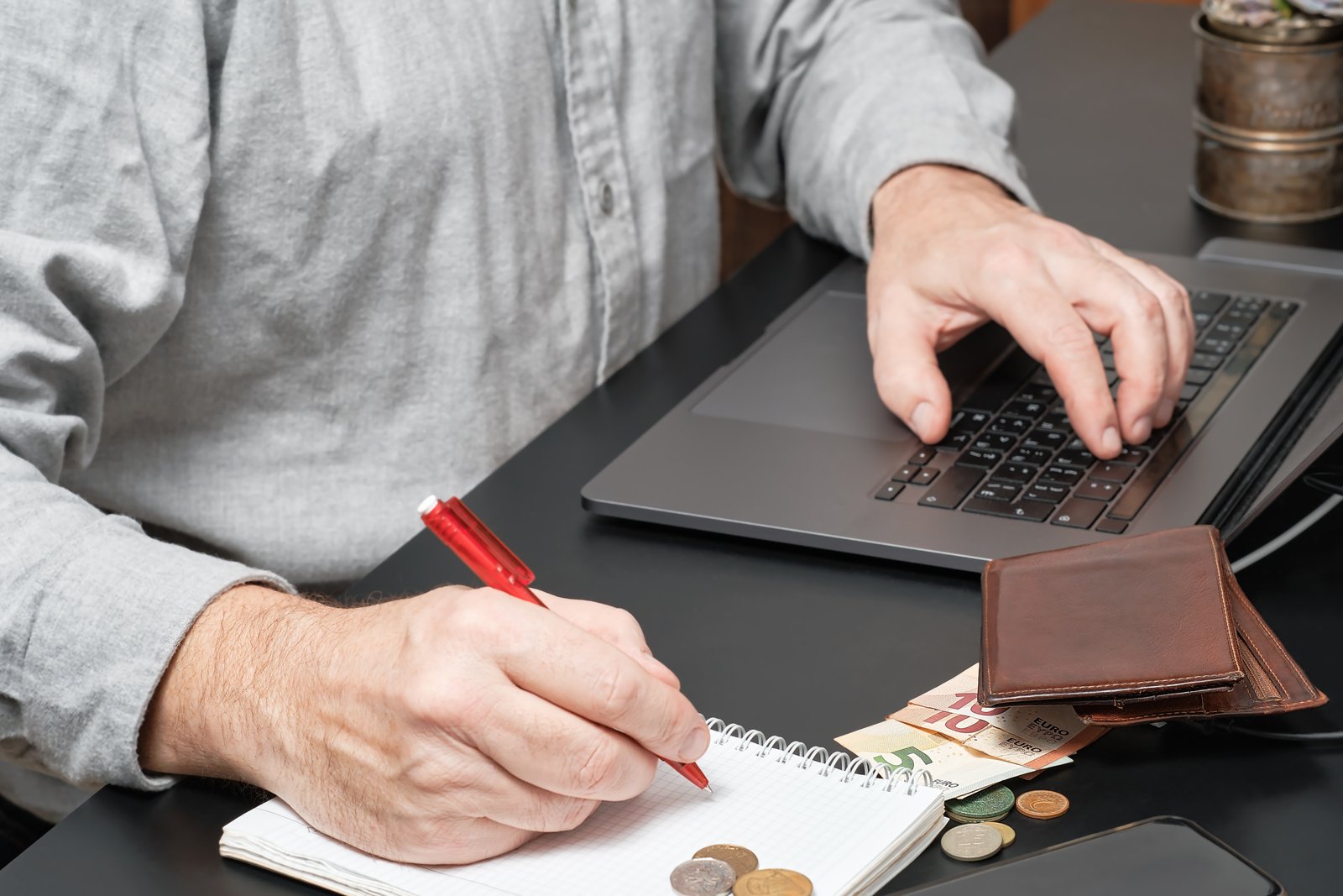 Business owner calculating profit margins with laptop, notebook, and financial documents on desk